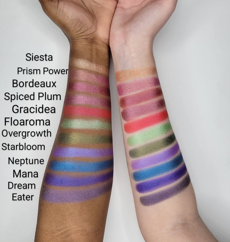 Puede incluir: Primer plano de dos brazos con muestras de sombra de ojos. Las muestras est&aacute;n etiquetadas con nombres como "Siesta", "Prism Power", "Bordeaux", "Spiced Plum", "Gracidea", "Floaroma", "Overgrowth", "Starbloom", "Neptune", "Mana", "Dream" y "Eater".