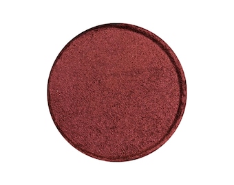 Op de afbeelding: Een enkele ronde oogschaduwpan met een diepe rode, bijna bordeauxrode kleur. De oogschaduw heeft een licht getextureerde, bijna fluweelzachte afwerking.