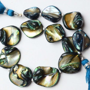 Può includere: Una collana di perle di madreperla di abalone iridescenti con un fiocco blu a ciascuna estremità. Le perle sono di colore verde scuro, blu e oro.