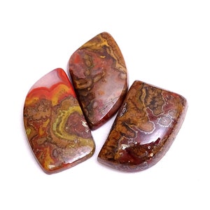 Può includere: Tre pietre preziose lucide con una miscela di colori rosso, marrone, giallo e bianco. Le pietre hanno una superficie liscia e lucida e un motivo naturale unico. Le forme sono irregolari, con bordi arrotondati.