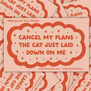May include: A rectangular waterproof vinyl sticker with a peach background and a coral-colored cloud-shaped design. The text reads "CANCEL MY PLANS THE CAT JUST LAID DOWN ON ME." Additional stickers are visible in the background.