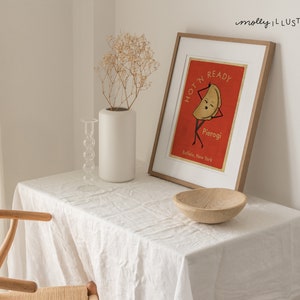 May include: A framed illustration of a pierogi with a face and arms, with the text "I'm ready, Hot'n Pierogi, Buffalo, New York". The illustration is on a red background and the frame is light wood.
