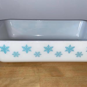 Puede incluir: Fuente rectangular blanca para hornear con un diseño de copos de nieve azul claro. La fuente tiene un borde ligeramente ensanchado y está hecha de un material duradero y resistente al calor. Ideal para hornear.