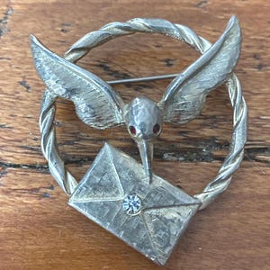 Raro broche vintage de latón Jeanne con forma de pájaro y letra en el pico, ojos rubí, década de 1950
