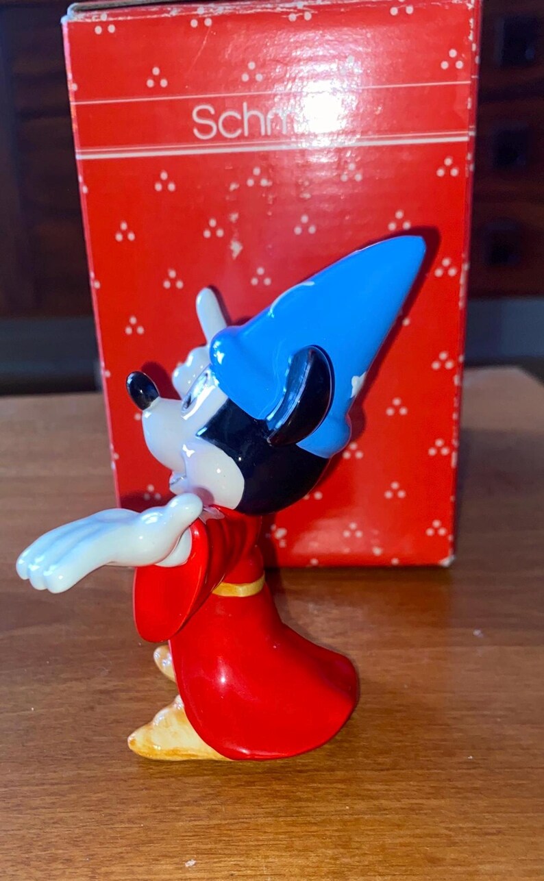K&ouml;nnte beinhalten: Eine Mickey Mouse-Figur als Zauberer, mit blauem Hut und rotem Gewand. Die Figur steht vor einer roten Schachtel mit dem Wort "Sch". Ein Sammlerst&uuml;ck.