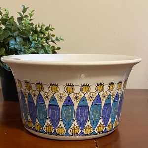 Può includere: Scodella in ceramica bianca con un motivo di pesci blu, gialli e neri. La ciotola ha un bordo largo e un fondo arrotondato.