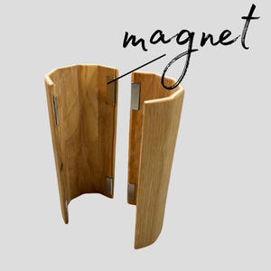 Peut inclure: Un objet incurvé en bois de couleur marron clair, avec une fermeture magnétique. Le mot "magnet" est écrit au-dessus de l'objet dans une police manuscrite. L'objet semble être une gaine ou un support.