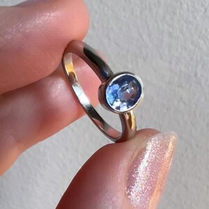 Pu&ograve; includere: Un anello d'argento con una pietra ovale blu chiaro.