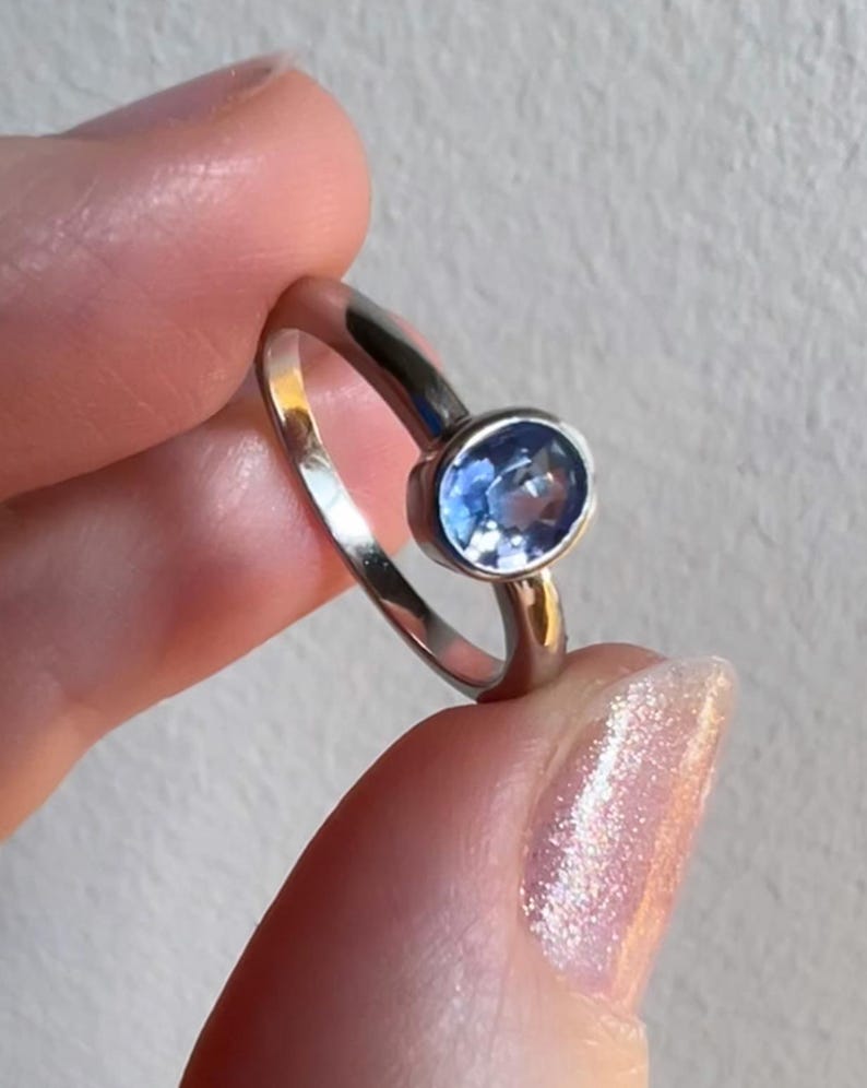 Pu&ograve; includere: Un anello d'argento con una pietra ovale blu chiaro.