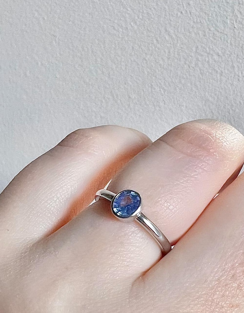 Pu&ograve; includere: Un anello d'argento con una pietra preziosa blu incastonata in una montatura a  bezel.