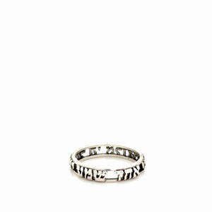May include: A silver ring featuring a cut-out design of Hebrew characters along the entire band. The metal has a polished finish with darkened recessed areas that highlight the lettering, creating a continuous band of script around the finger.