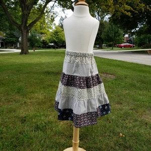 May include: A multi-coloured tiered skirt with floral and striped patterns. The skirt is made of a soft, comfortable fabric and has a flowy silhouette.