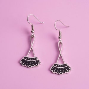May include: A pair of silver earrings with black and white polka dot designs. The earrings are shaped like a fan or a ruffle.