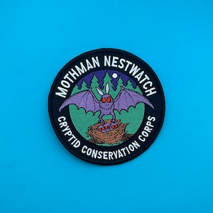 May include: Black and white embroidered patch with the text "Mothman Nestwatch Cryptid Conservation Corps" around a green forest scene with a purple bat with red eyes and a nest of eggs.