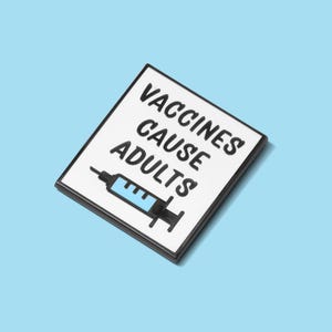 May include: A rectangular pin with a white background and black border. The pin features the text "VACCINES CAUSE ADULTS" in black, with a blue and black syringe illustration below the text. The pin is set against a light blue background.
