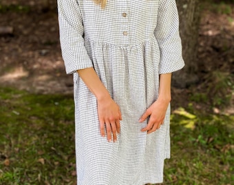 May include: A white and black checkered midi dress with a button-up front and 3/4 sleeves.