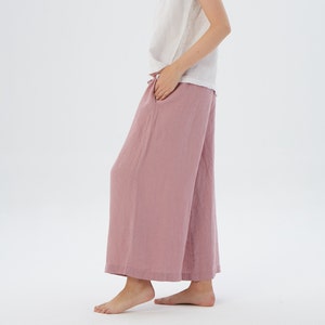 Puede incluir: Un pantal&oacute;n de pierna ancha en color rosa polvoriento. El pantal&oacute;n est&aacute; hecho de una tela de lino suave y tiene un corte holgado.