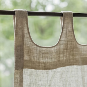 May include: A beige curtain panel with a textured, woven appearance hanging from a dark brown rod. The top of the curtain features wide, integrated fabric loops that slide directly onto the rod, creating a simple, clean header design.