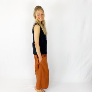 May include: A woman wearing a black sleeveless top and a rust-colored linen skirt with a pocket. The skirt is gathered at the waist and falls to the ankles.