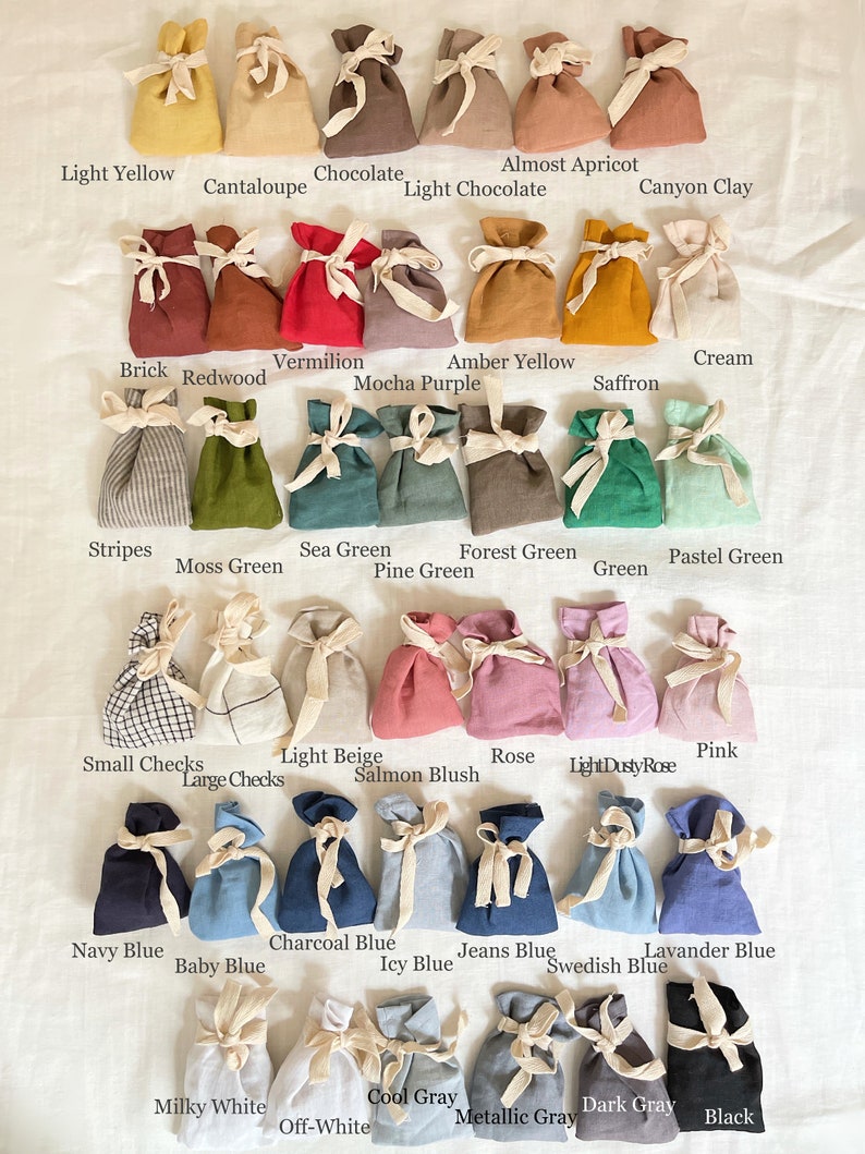 May include: A collection of 36 small fabric drawstring bags in various colors and patterns. The bags are arranged in rows, with each row representing a different color or pattern. The colors include light yellow, chocolate, cantaloupe, almost apricot, light chocolate, canyon clay, vermilion, amber yellow, brick, redwood, mocha purple, stripes, moss green, sea green, forest green, pine green, cream, saffron, pastel green, green, small checks, large checks, light beige, rose, pink, salmon blush, light dusty rose, navy blue, charcoal blue, jeans blue, lavender blue, baby blue, icy blue, swedish blue, milky white, cool gray, dark gray, off-white, metallic gray, and black.
