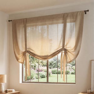 May include: A beige, semi-sheer tie-up curtain panel made of a textured fabric. The curtain is suspended from a dark metal rod and features two vertical fabric ties that gather the bottom edge, creating a soft, draped, scalloped effect.