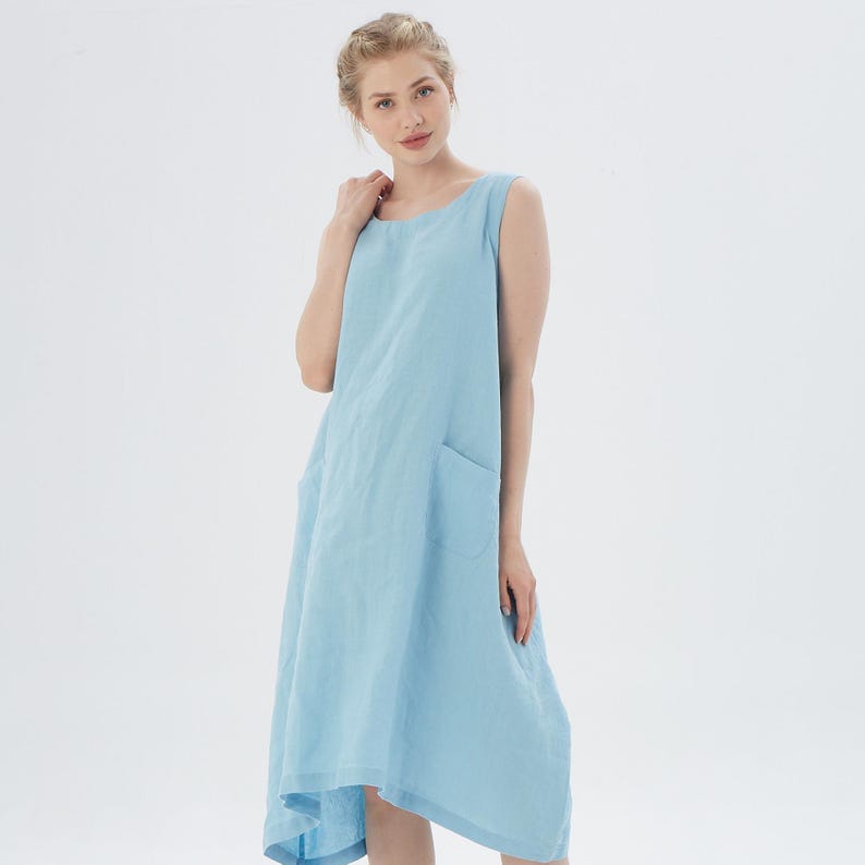 May include: A light blue sleeveless linen dress with a single pocket on the left side.