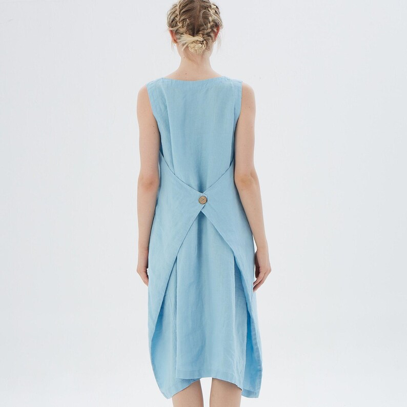 May include: A light blue sleeveless linen dress with a unique criss-cross back design and a single button closure.