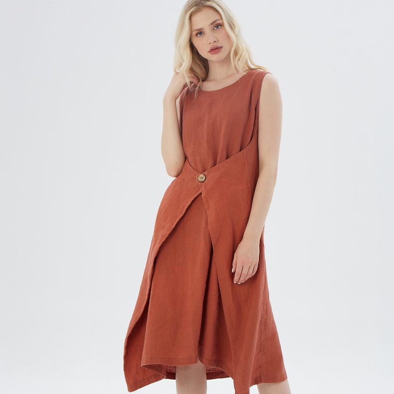 May include: A rust-coloured linen dress with a wrap-style design and a single button fastening at the waist.