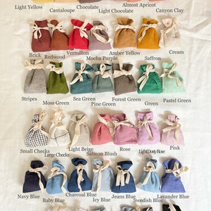 May include: Color chart of fabric swatches in the form of small drawstring bags. The chart includes colors like light yellow, cantaloupe, chocolate, light chocolate, almost apricot, canyon clay, brick, redwood, vermilion, amber yellow, mocha purple, saffron, cream, stripes, moss green, sea green, forest green, pine green, pastel green, green, small checks, light beige, rose, pink, large checks, salmon blush, light dusty rose, navy blue, baby blue, charcoal blue, icy blue, jeans blue, swedish blue, lavander blue, milky white, cool gray, dark gray, off-white, metallic gray, and black.