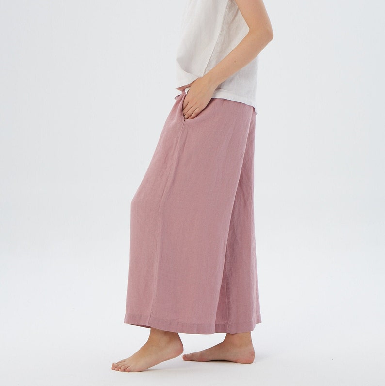 Puede incluir: Un pantal&oacute;n de pierna ancha en color rosa polvoriento. El pantal&oacute;n est&aacute; hecho de una tela de lino suave y tiene un corte holgado.