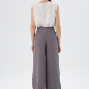 Puede incluir: Una camiseta sin mangas de color claro combinada con unos pantalones culotte grises de pernera ancha. El conjunto est&aacute; confeccionado con una tela suave y fluida. El modelo se ve desde atr&aacute;s, mostrando el dise&ntilde;o minimalista y el ajuste relajado de la ropa.