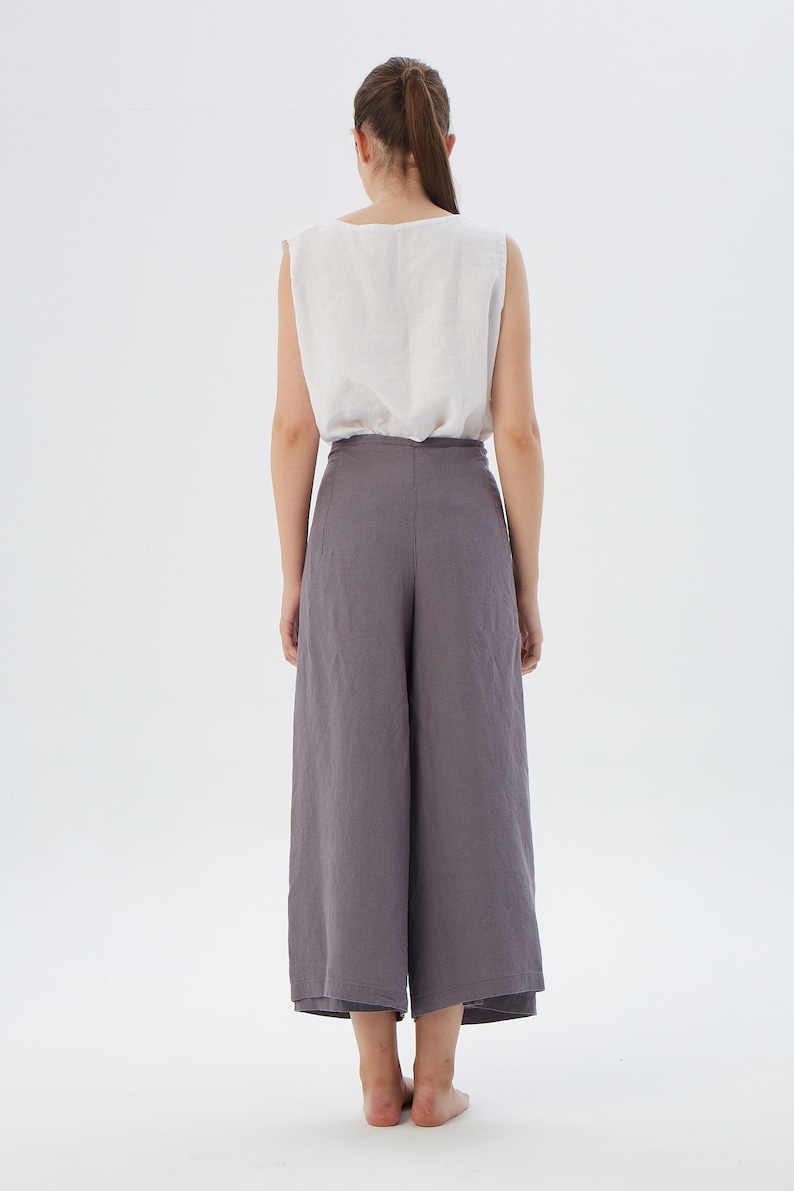 Puede incluir: Una camiseta sin mangas de color claro combinada con unos pantalones culotte grises de pernera ancha. El conjunto est&aacute; confeccionado con una tela suave y fluida. El modelo se ve desde atr&aacute;s, mostrando el dise&ntilde;o minimalista y el ajuste relajado de la ropa.