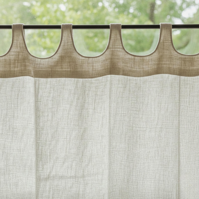 a close-up view of a beige curtain with a textured fabric, hanging from a rod with a curved design.