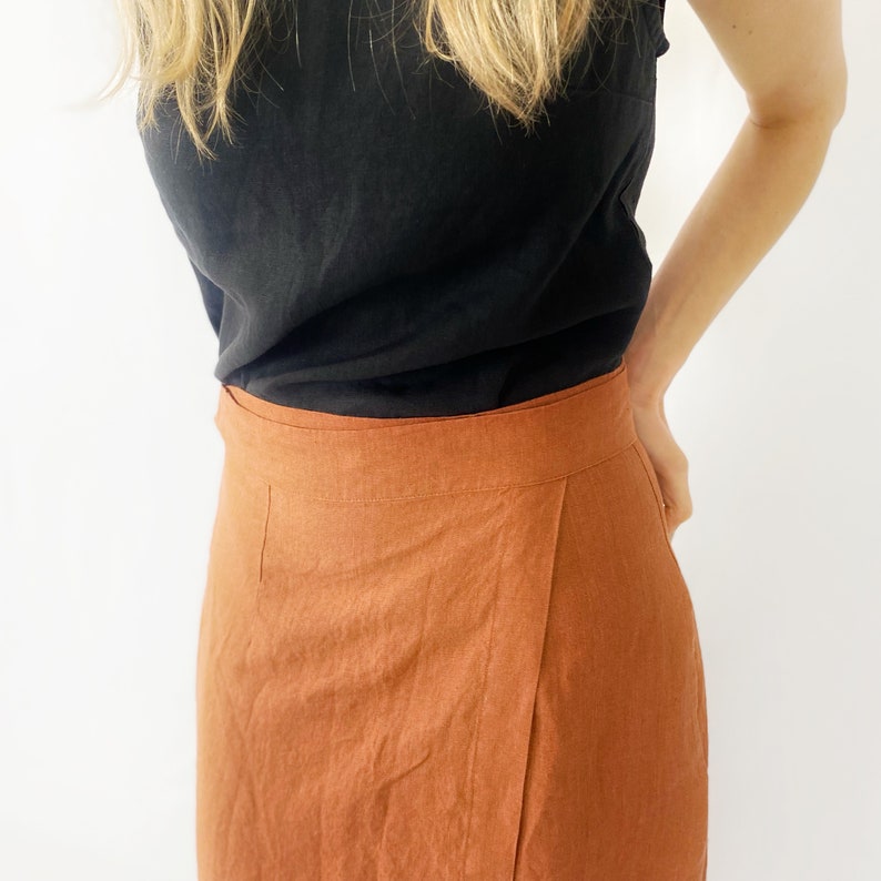May include: A rust-colored linen wrap skirt with a black tank top.