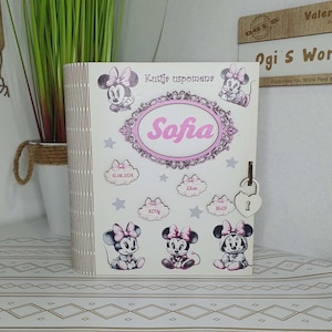 Puede incluir: Caja de recuerdos de madera con ilustraciones de Minnie Mouse y el nombre "Sofia" en rosa. La caja incluye detalles como la fecha 15.08.2024, el peso 4270g, la altura 53cm y la hora 16:01. Un candado en forma de corazón asegura la caja.