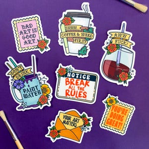 May include: Ten colorful stickers with motivational and humorous messages for artists. The stickers feature a variety of designs, including a coffee cup, a paintbrush, and a flower.