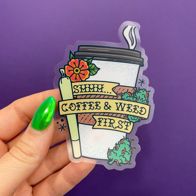 May include: A clear sticker with a cartoon illustration of a coffee cup and a joint. The text on the sticker reads "Shhh... Coffee & Weed First."