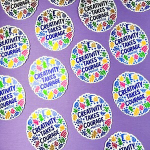 May include: A collection of circular stickers featuring the text "CREATIVITY TAKES COURAGE -MATISSE" in dark blue, surrounded by a colorful border of abstract leaf and organic shapes in shades of yellow, green, pink, and light blue.