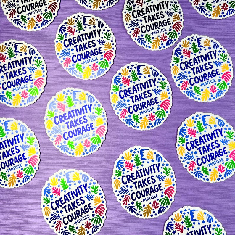May include: A collection of circular stickers featuring the text "CREATIVITY TAKES COURAGE -MATISSE" in dark blue, surrounded by a colorful border of abstract leaf and organic shapes in shades of yellow, green, pink, and light blue.