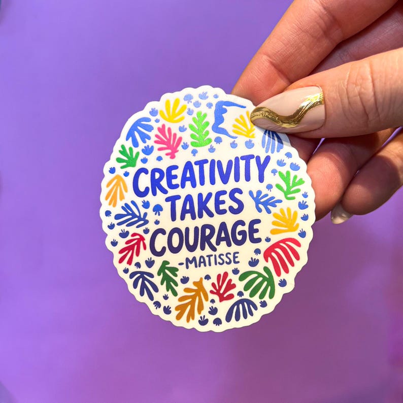 May include: A round, scalloped-edge sticker with a cream background featuring the blue text 'CREATIVITY TAKES COURAGE -MATISSE' at the center, surrounded by a colorful pattern of abstract organic shapes in yellow, pink, green, and red.