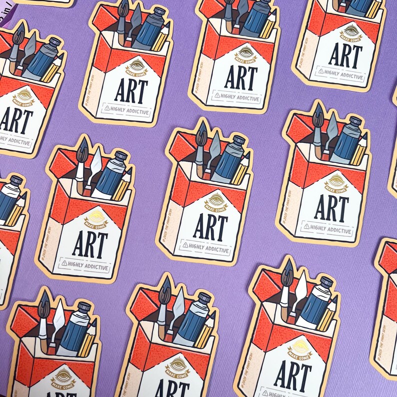 K&ouml;nnte beinhalten: Eine Sammlung von Aufklebern mit einem rot-wei&szlig;en Zigarettenschachtel-Design, auf dem die W&ouml;rter "ART" und "HIGHLY ADDICTIVE" stehen. Die Schachtel enth&auml;lt Kunstutensilien wie Farbtuben, Pinsel und Bleistifte. Der Hintergrund ist einfarbig lila.