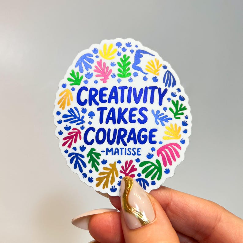 May include: A circular sticker with a white background featuring the blue text CREATIVITY TAKES COURAGE -MATISSE in the center. The design is surrounded by a colorful border of abstract organic leaf and coral-like shapes in yellow, pink, green, and blue.