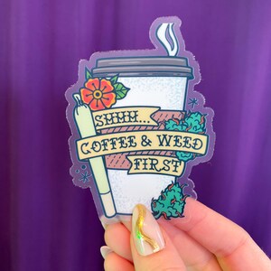 May include: A clear sticker with a cartoon illustration of a coffee cup and a joint. The text on the sticker reads "SMMH... COFFEE & WEED FIRST".