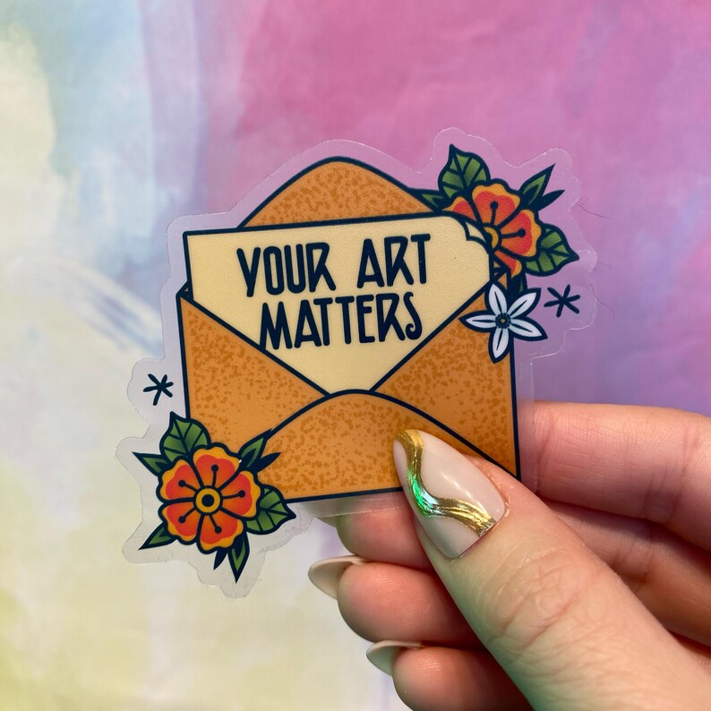 Op de afbeelding: Een transparante sticker met een gele envelop en bloemen. De envelop bevat een wit briefje met de tekst "Your Art Matters".