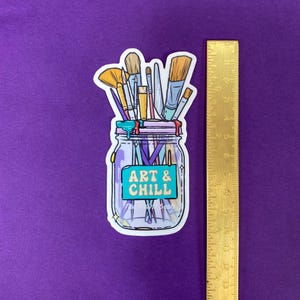 Puede incluir: Una pegatina con un tarro de cristal lleno de pinceles y una etiqueta turquesa que dice "Art & Chill".