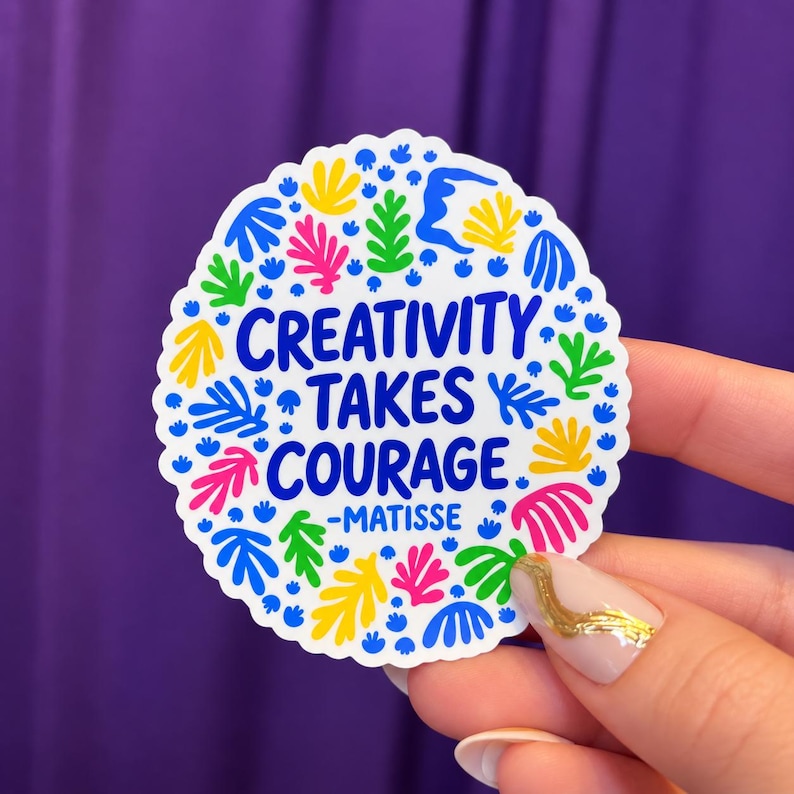 May include: A circular sticker with a white background featuring the blue text CREATIVITY TAKES COURAGE -MATISSE. The design is surrounded by a colorful pattern of small, abstract organic shapes in shades of blue, green, yellow, and pink.