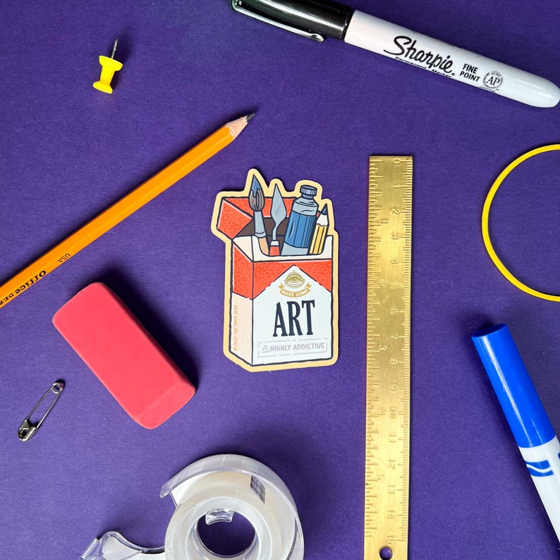 K&ouml;nnte beinhalten: Eine Ansammlung von Kunstbedarf auf violettem Hintergrund. Enth&auml;lt einen Aufkleber mit dem Wort "ART" und Kunstwerkzeugen, einen Bleistift, einen Radiergummi, ein Lineal, Klebeband, einen Marker, eine Rei&szlig;zwecke und eine Sicherheitsnadel.