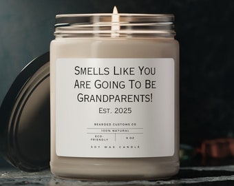 May include: A beige soy wax candle with a white label that reads "Smells Like You Are Going To Be Grandparents! Est. 2025". The candle is in a clear glass jar with a black lid.