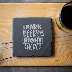 May include: Black slate coaster with the text "Park Beer Right Here" in white lettering. The coaster features a small graphic of a beer can and bottle.