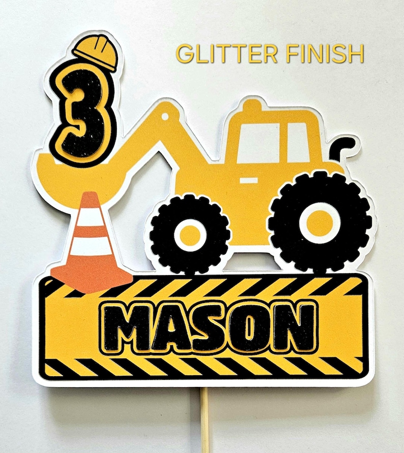 K&ouml;nnte beinhalten: Gelber Baumaschinen-Kuchentopper mit einer schwarzen Zahl 3, einem Baukegel und dem Namen "MASON" auf einem gelb-schwarz gestreiften Schild. Der Topper hat eine Glitzer-Oberfl&auml;che.